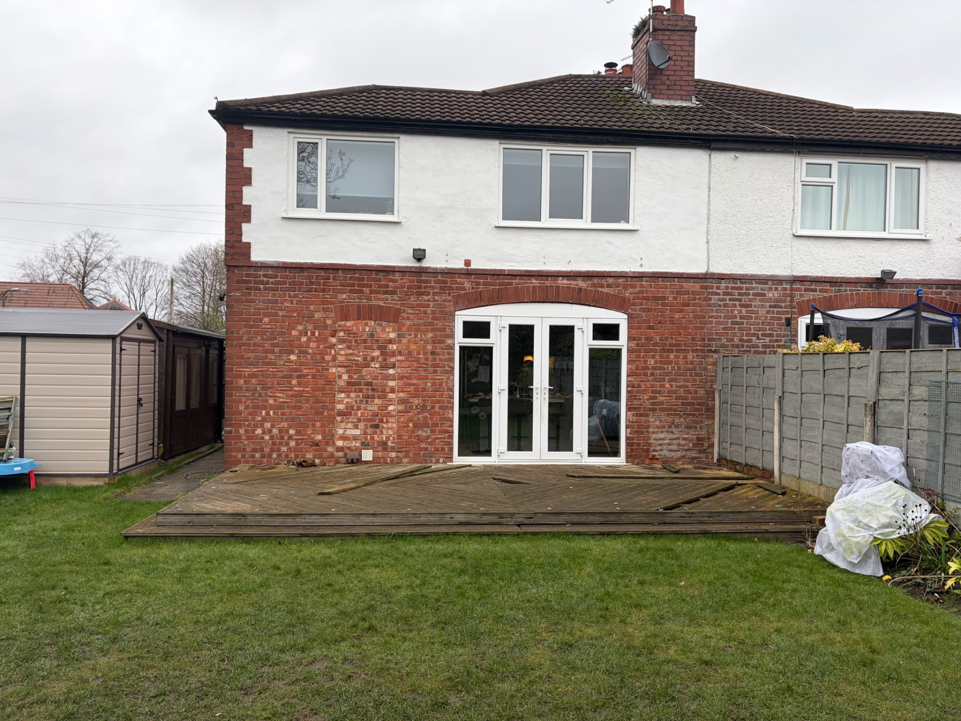 Semi-detached Urmston home before installation, with old window frames and decking